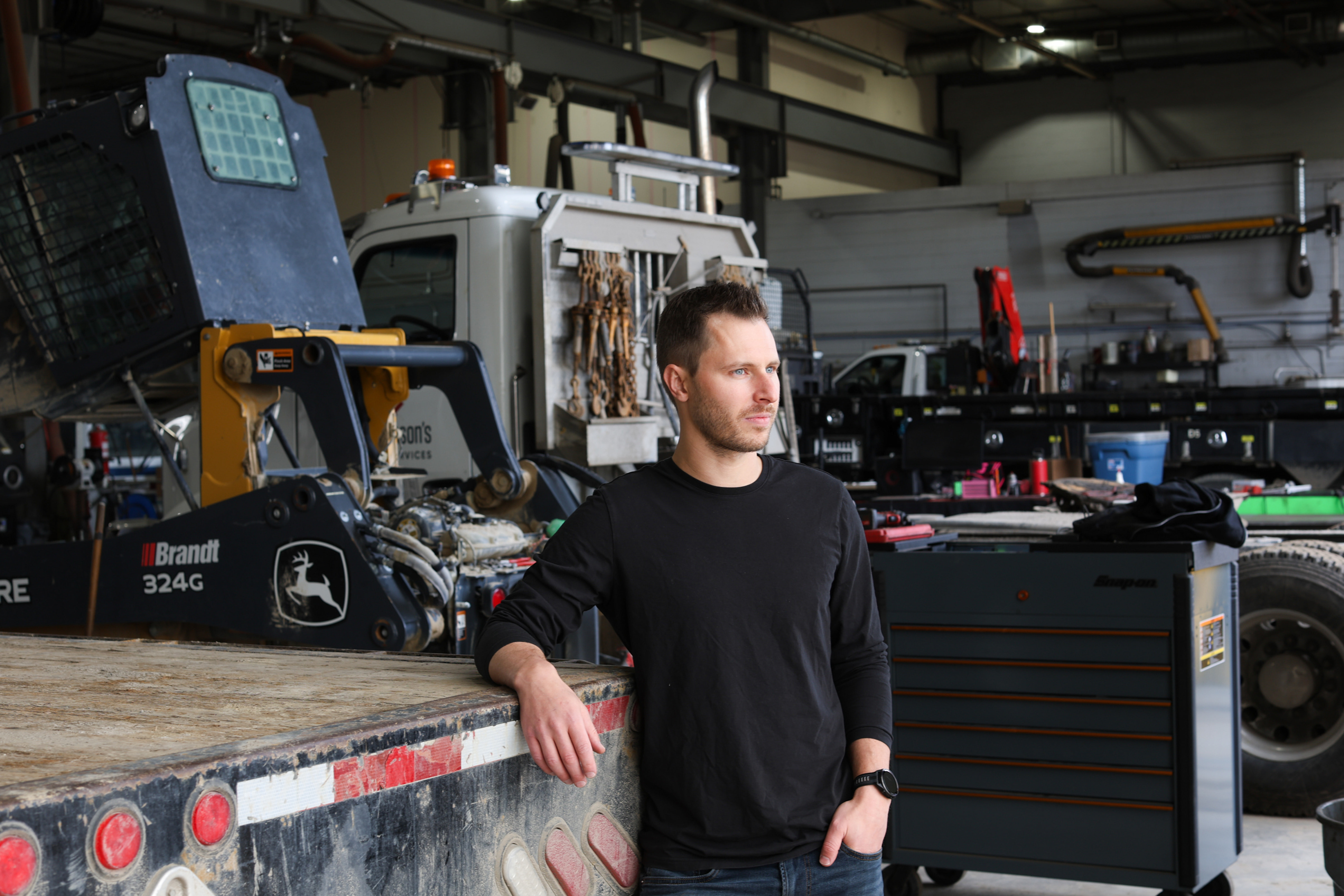 Fabian Bonjean in a Foothills Group bay beside a John Deere skid steer